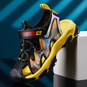 Black and yellow sandal with colorful sole on a blue and white striped background