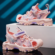 Pink children's sandals with purple accents on a reflective surface and blue striped background