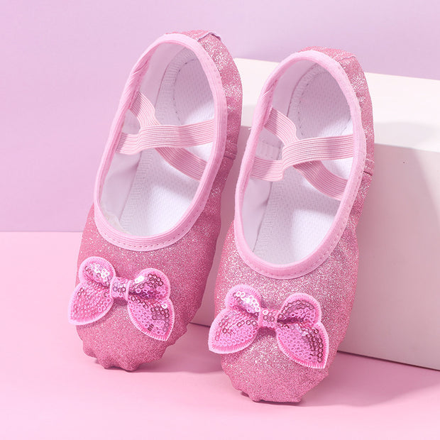 Pink glittery ballet shoes with bows on a pink background