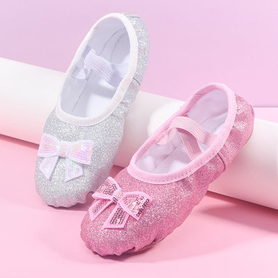 Pair of glittery children's shoes with bows on a pink background